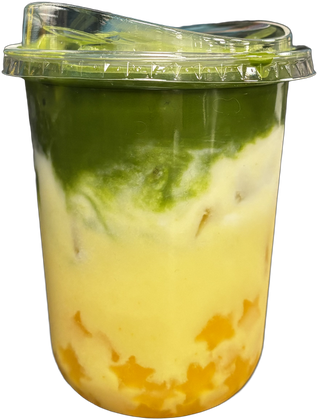 Tall clear cup layered with golden mango, coconut cream and dark green matcha, mango star jellies at the bottom