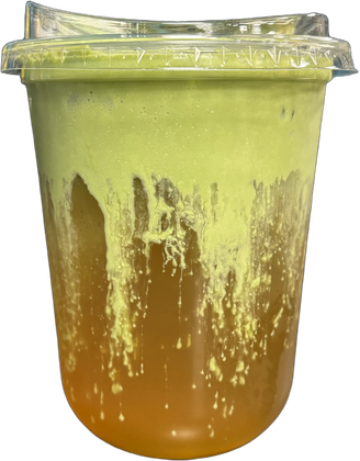 Tall clear cup of amber jasmine green tea under a thick layer of green matcha cold foam, streaking down the sides