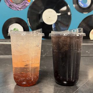Two custom sodas with boba, in front of a wall of vinyl records